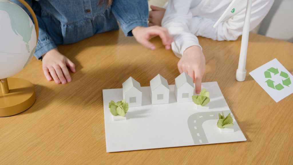 Children learning about renewable energy with model houses and globe on a table